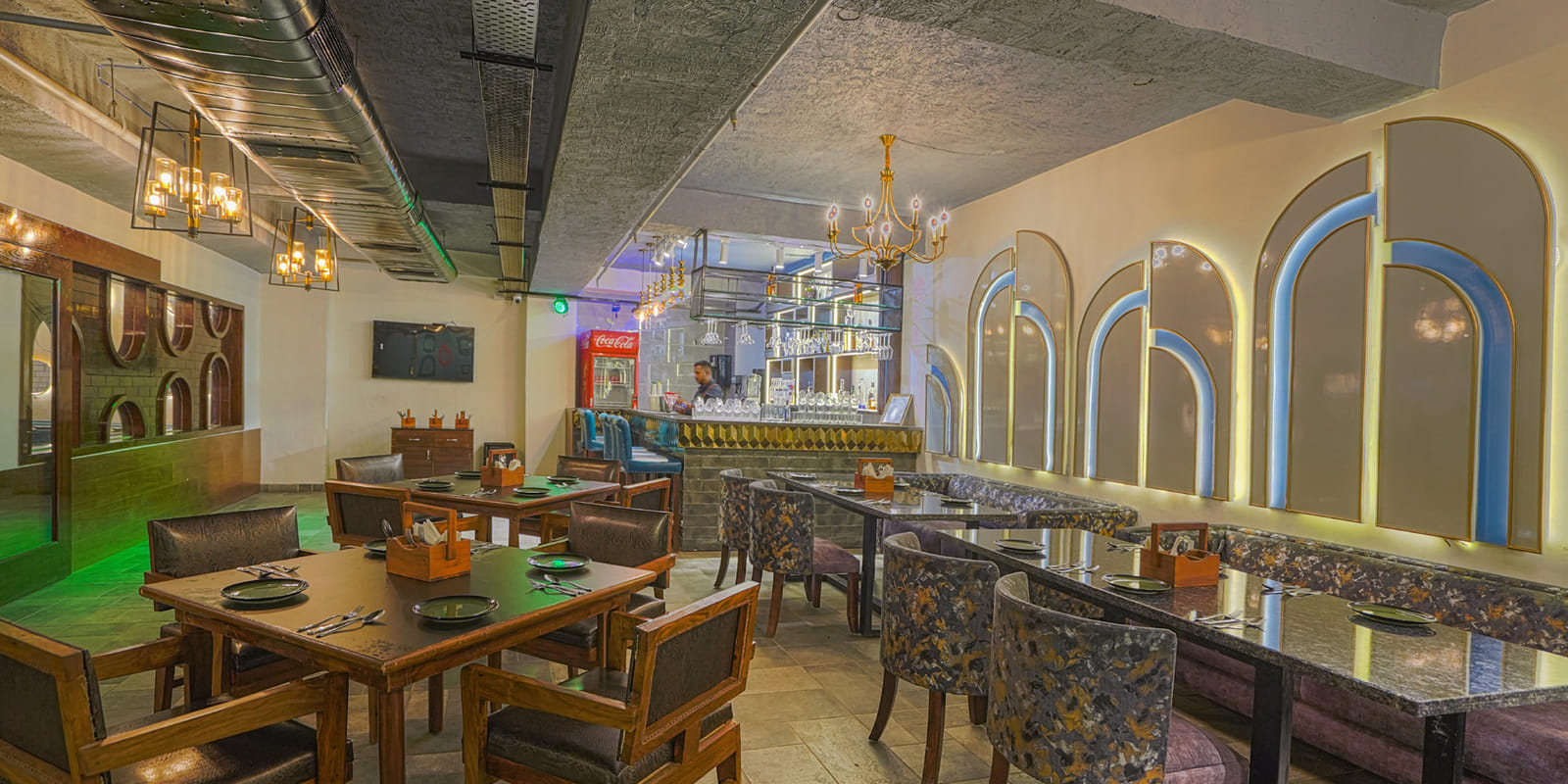 The Restaurant at Escala Hotel in Amritsar, its wooden tables set before arched niches and a lit bar counter