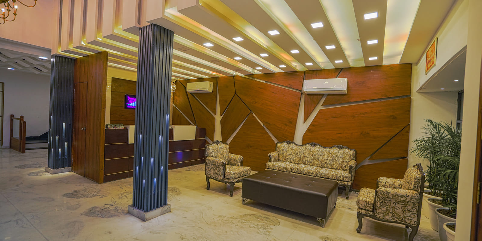 The lobby at Escala Hotel in Amritsar, with sofas and armchairs set against a timber-panelled wall under a lit ceiling