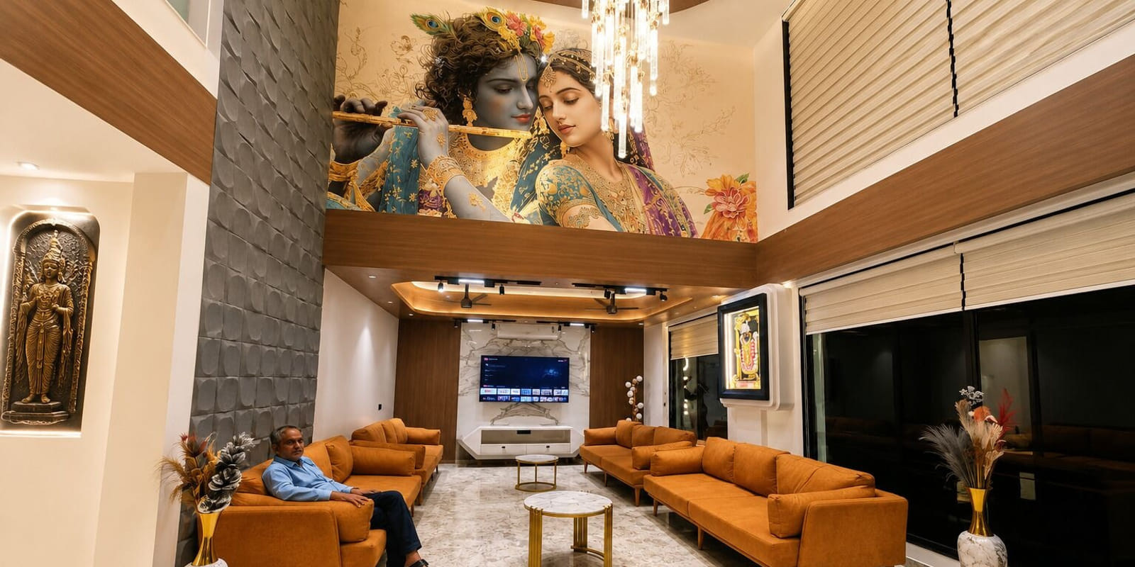 The lobby lounge at Hotel Shree Radhe By White Panda in Dwarka, with orange sofas below a mural and a chandelier