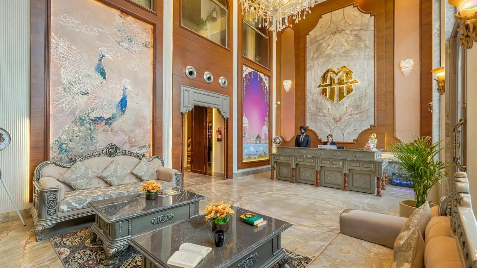 The double-height reception lobby at Marrion Hotel, with staff at the marble desk, a chandelier overhead and a peacock mural
