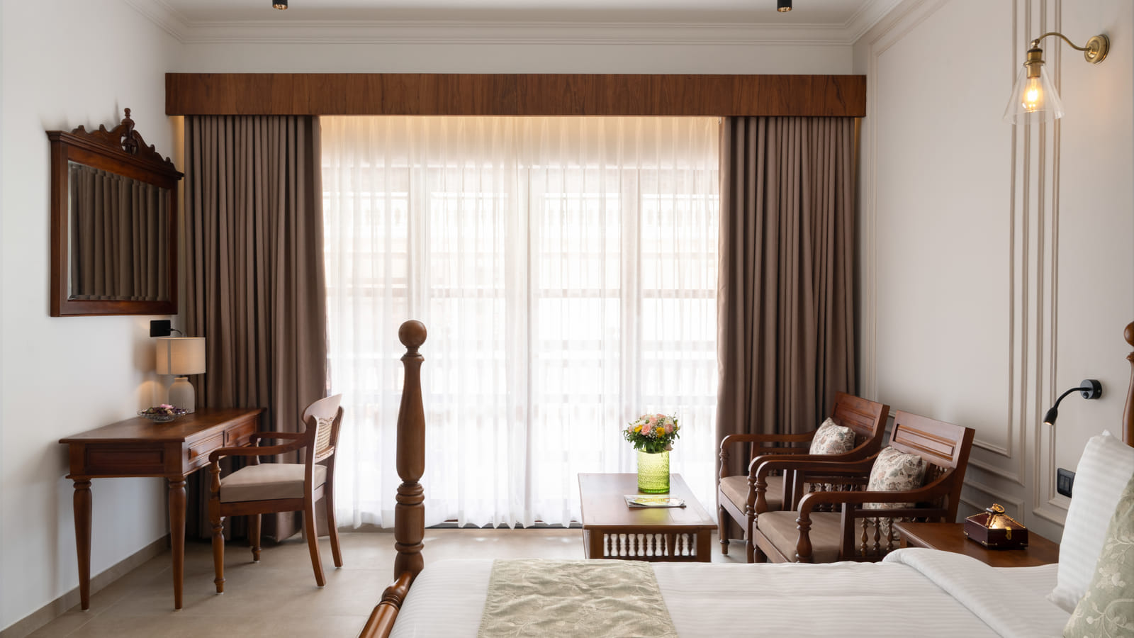 Pool View Room writing desk with a cushioned chair, framed mirror above and traditional Kerala lamp, Sanskreti