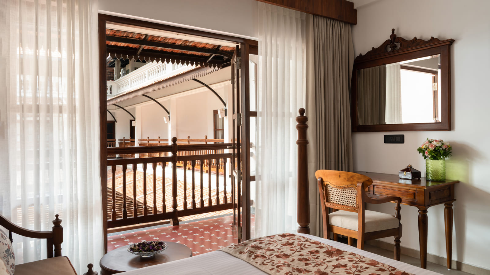 Pool View Twin Room verandah with a cushioned chair and side table looking onto the pool deck, Sanskreti
