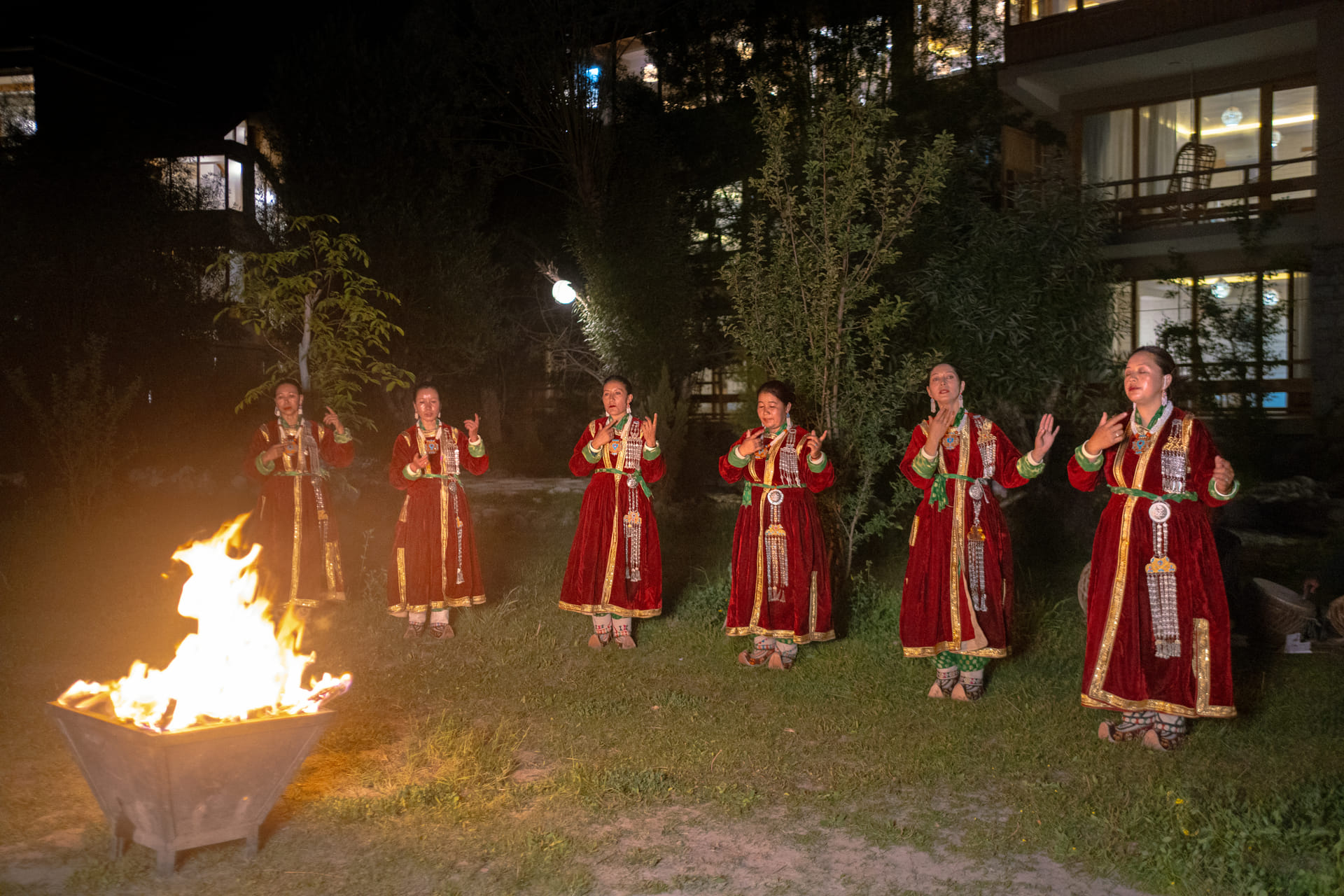 Ladakhi dancers in red kos sulma performing by a fire during a cultural evening