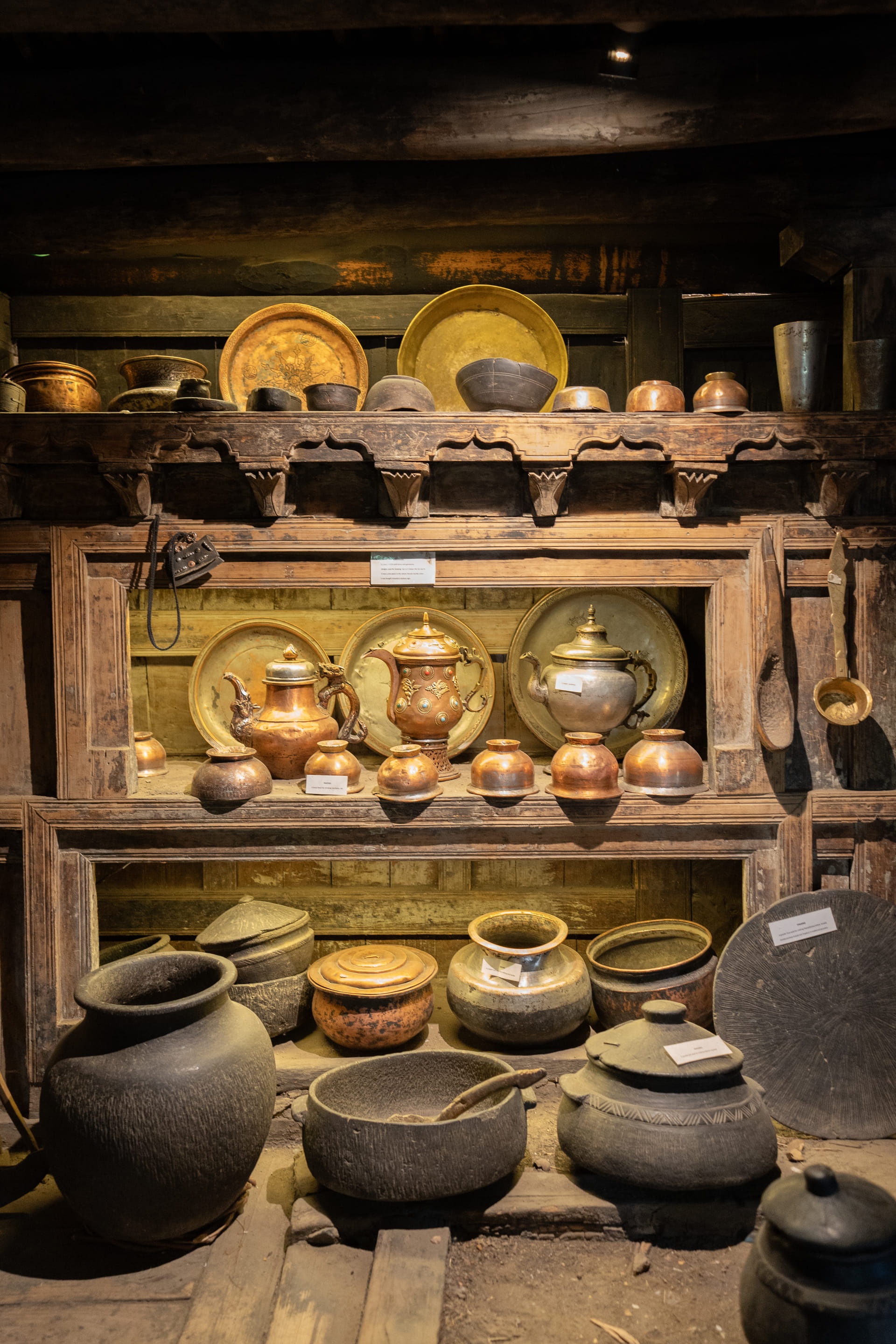 Antique copper and brass vessels on a carved wooden shelf