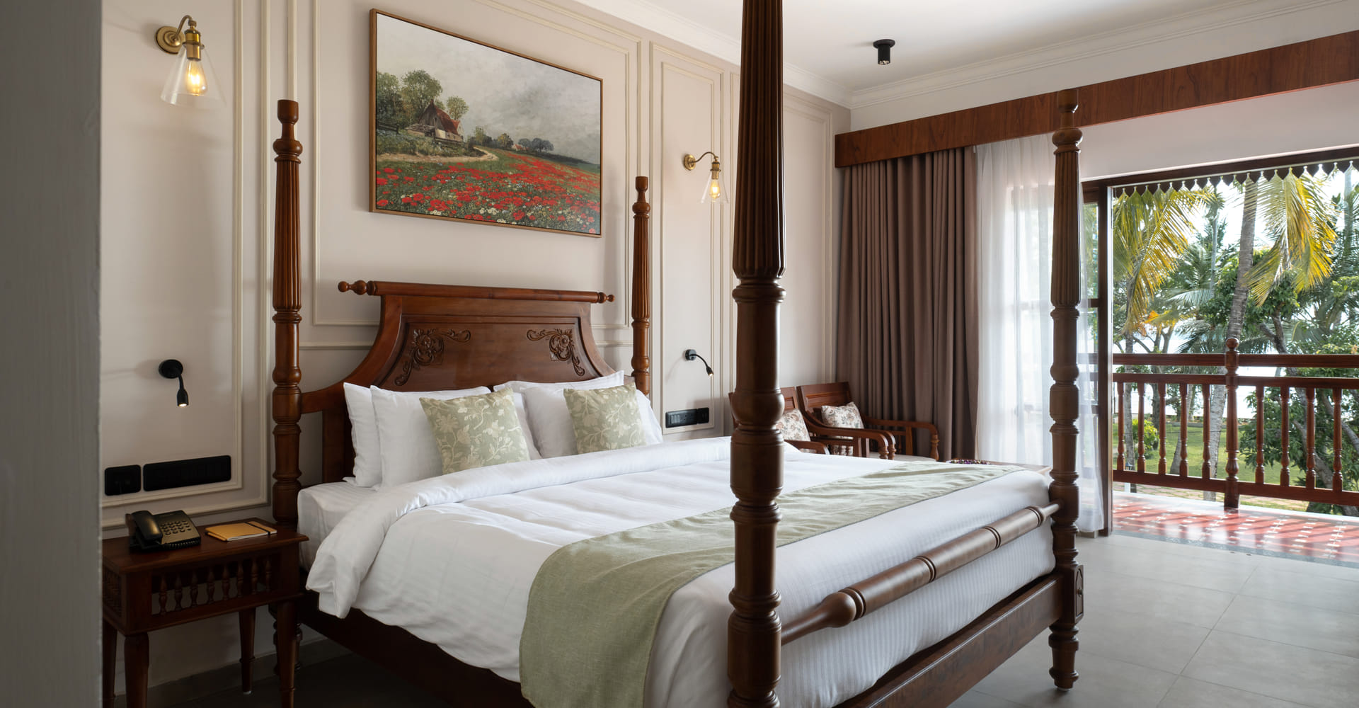 Lake-view guest room with a four-poster king bed, cane headboard and balcony doors opening onto palms and Vembanad Lake, Sanskreti