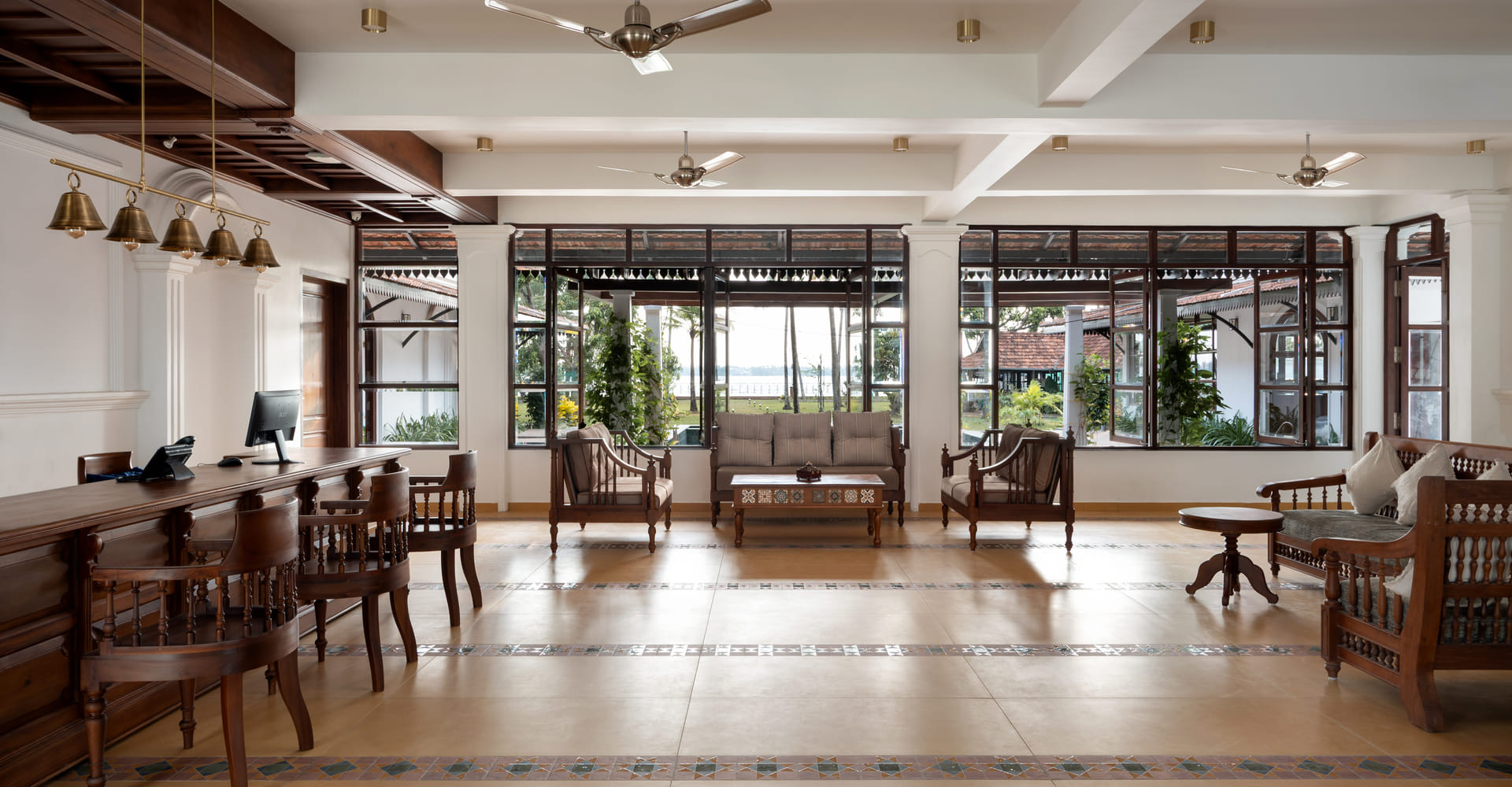 Sanskreti lobby lounge with cane sofas, coffee tables and tall windows opening to the lake and palm garden, Kumbalanghi, Kochi