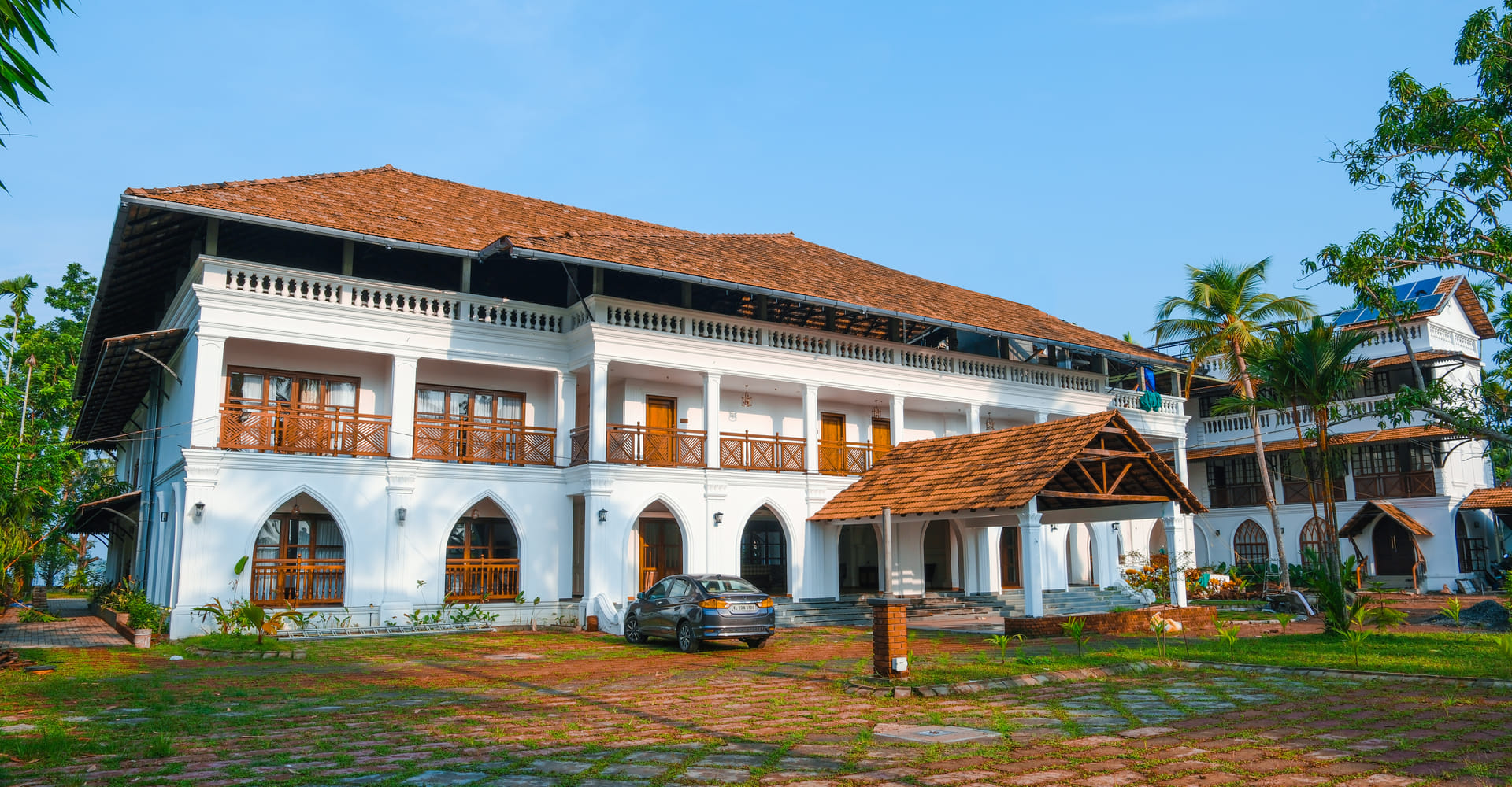 Sanskreti courtyard with arched white verandahs, terracotta-tiled roofs and a landscaped garden, Kumbalanghi, Kochi