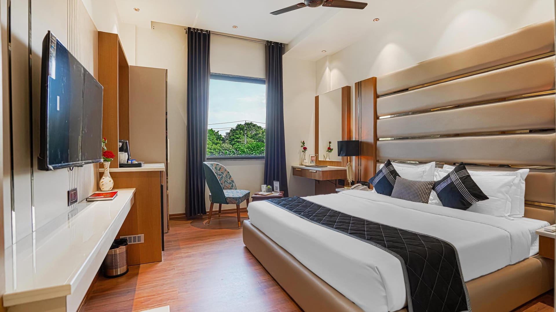 A Deluxe room at Aura Bliss, with a fluted headboard, a dark runner across the bed, a wall-mounted television