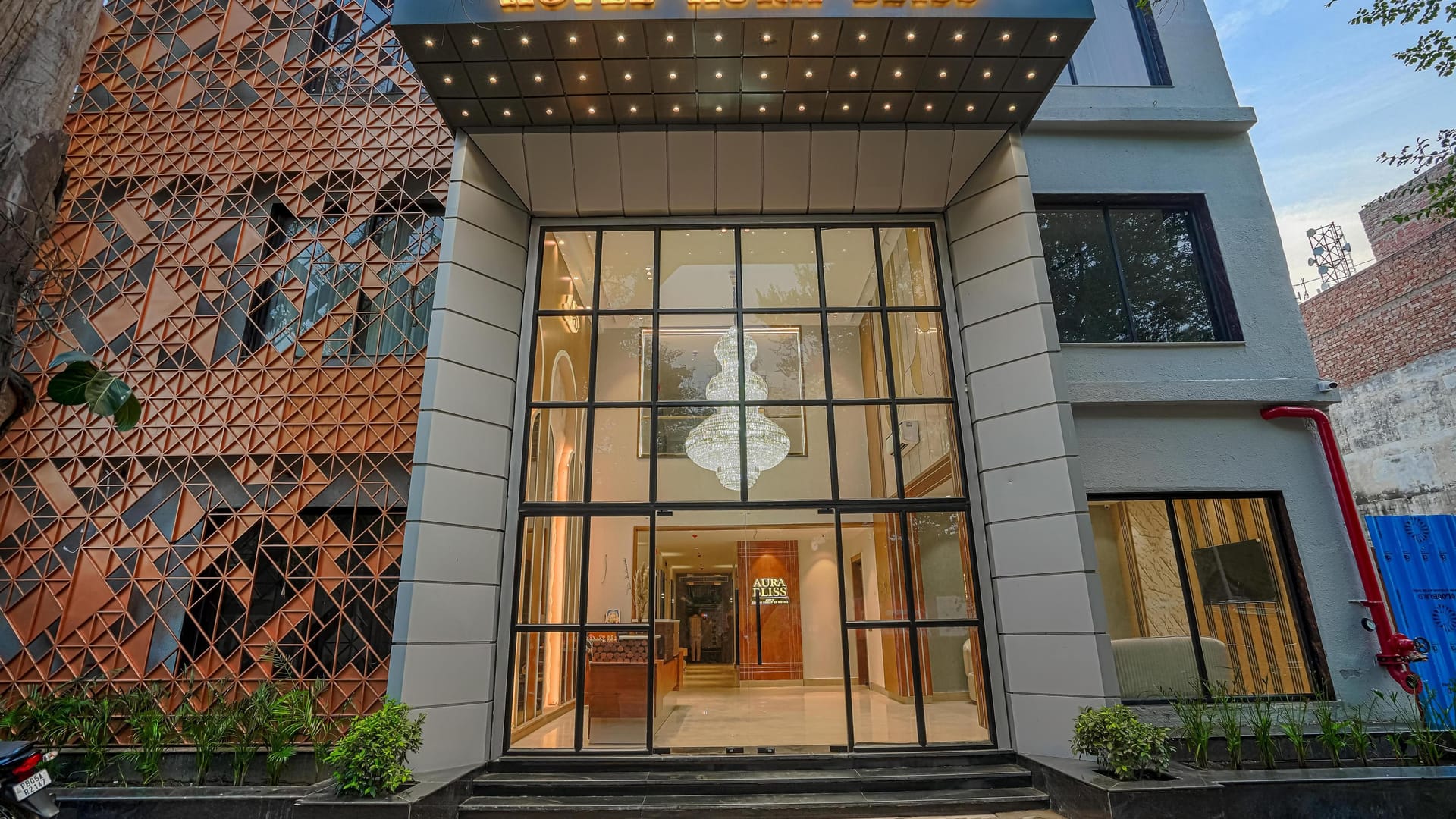 The entrance to Aura Bliss in Amritsar, a double-height glass front set into a brick lattice facade with lit signage