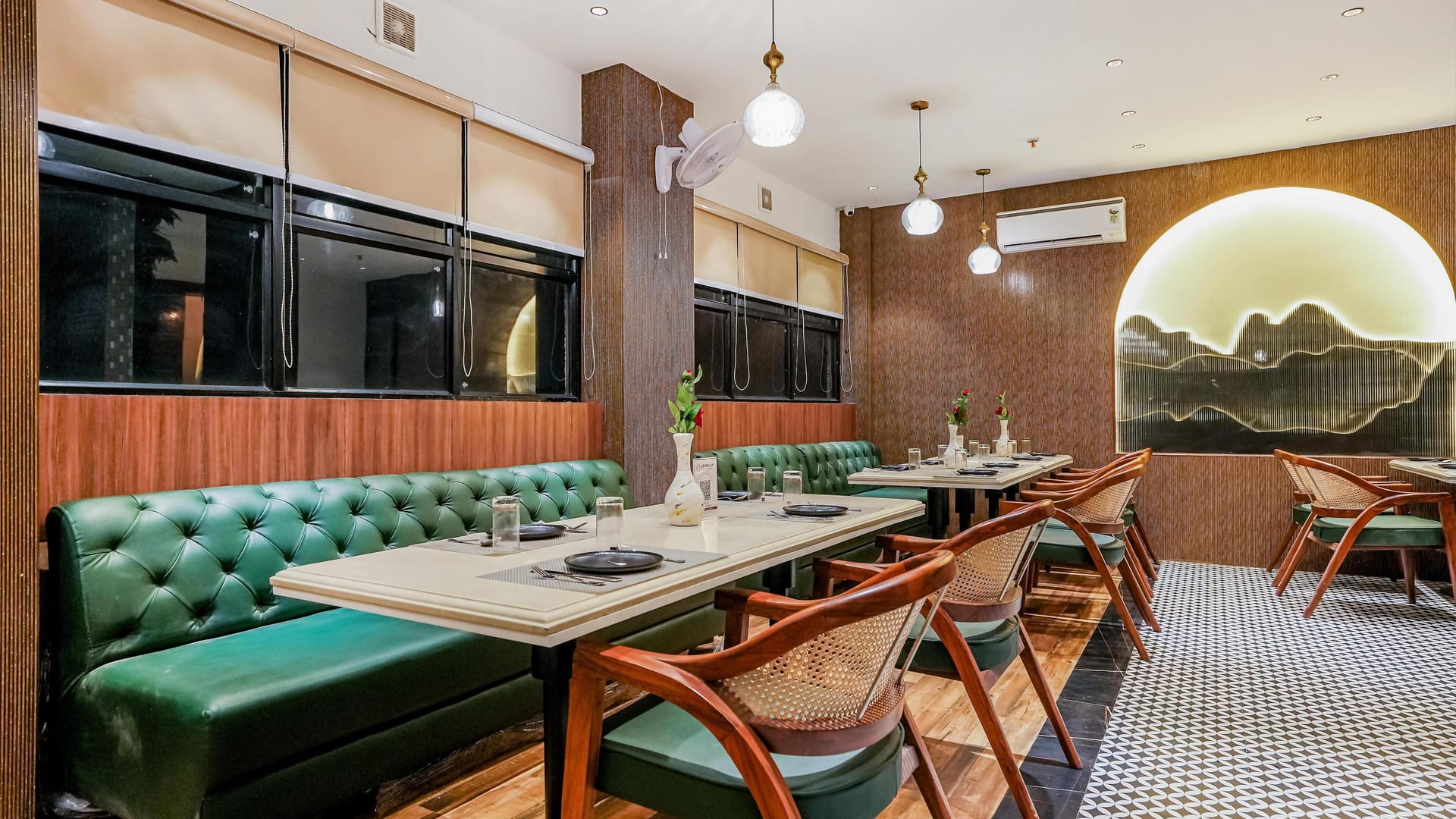 The Restaurant at Aura Bliss, with a green tufted banquette running along tables and wooden chairs, below pendant lights