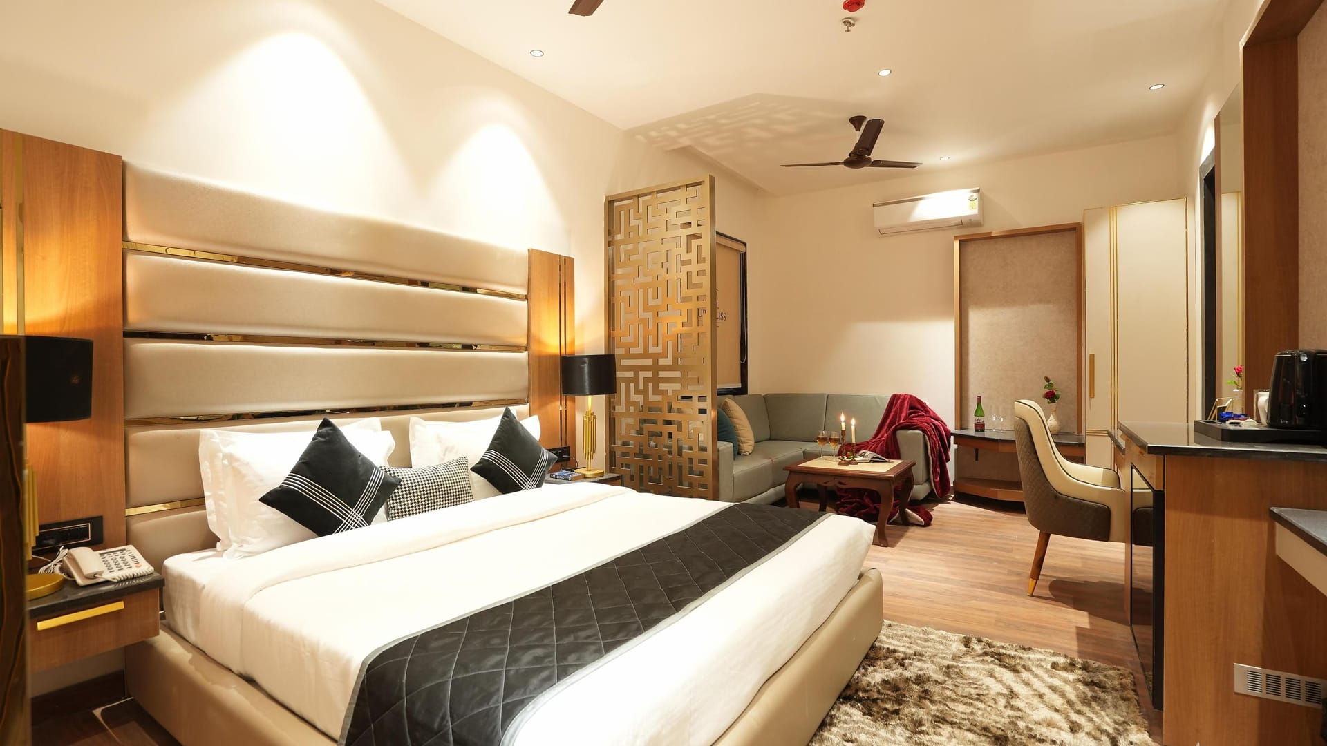 A Suite at Aura Bliss, with a fluted headboard and dark bed runner, a carved screen beside the bed
