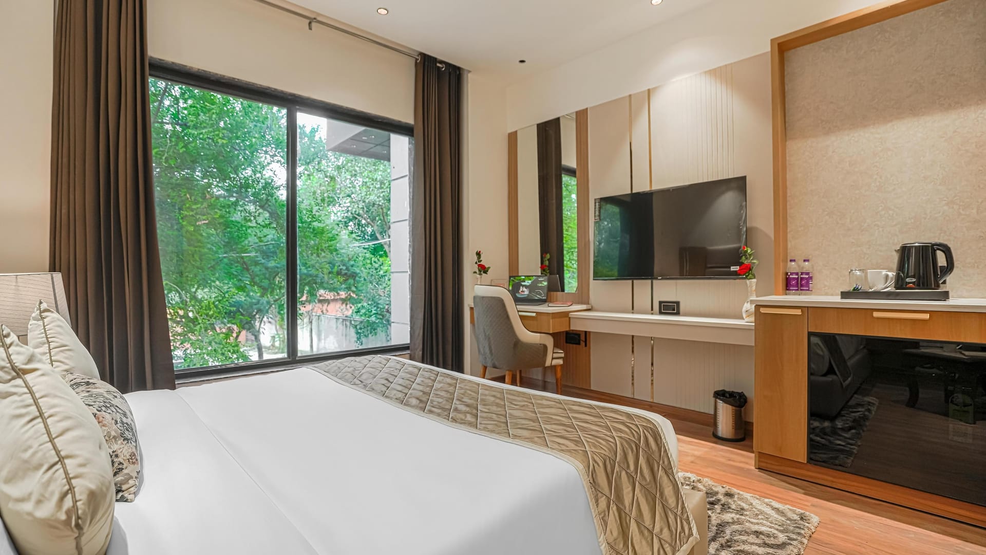 A Superior room at Aura Bliss, with a long desk and kettle beneath a wall-mounted television, an office chair