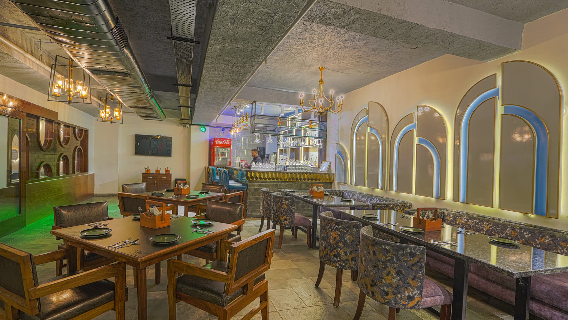 The lounge at Escala Hotel, with a long counter and high stools on one side and wooden tables