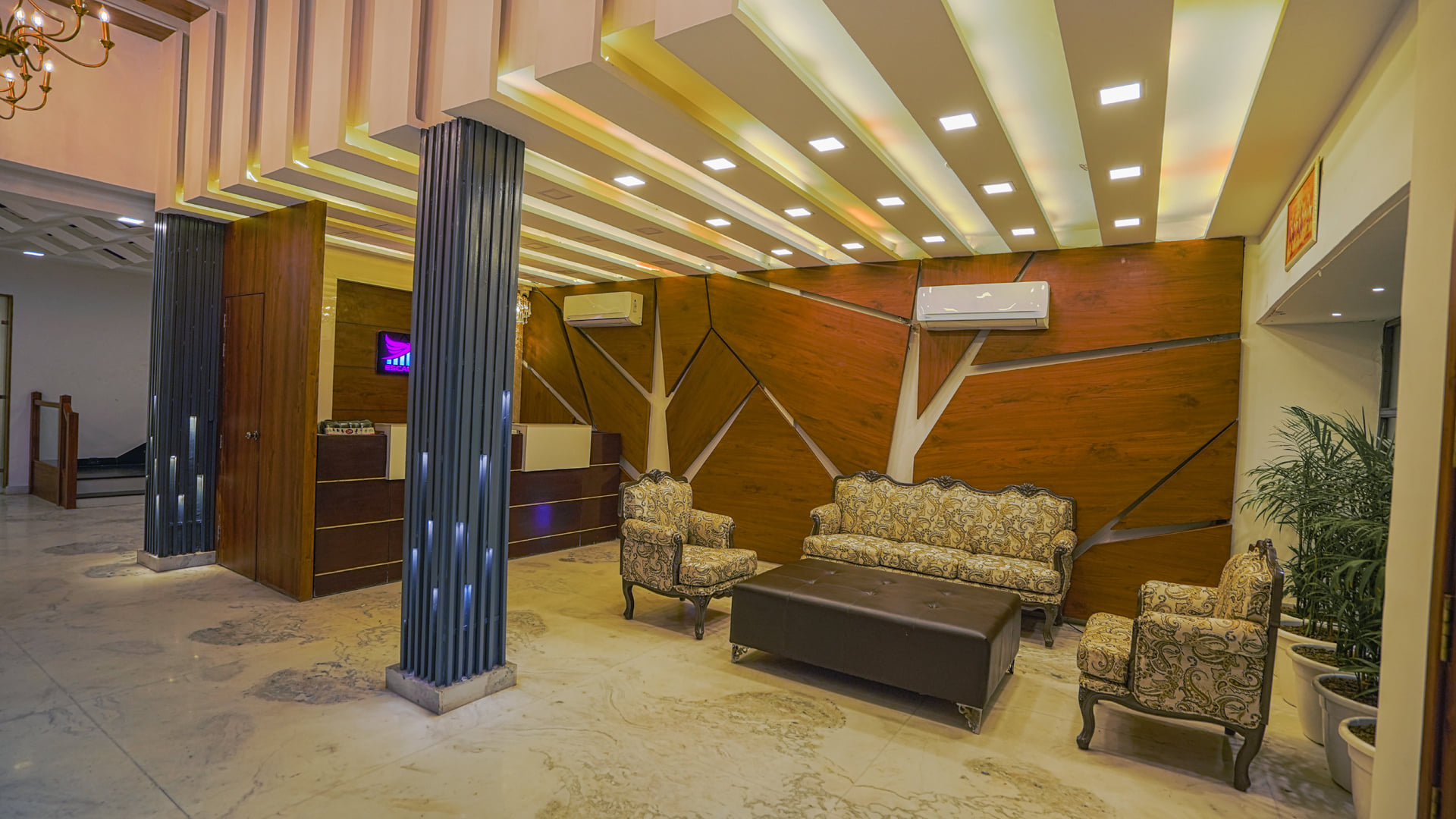 The lobby at Escala Hotel, with armchairs set around a low table below a slatted timber ceiling feature