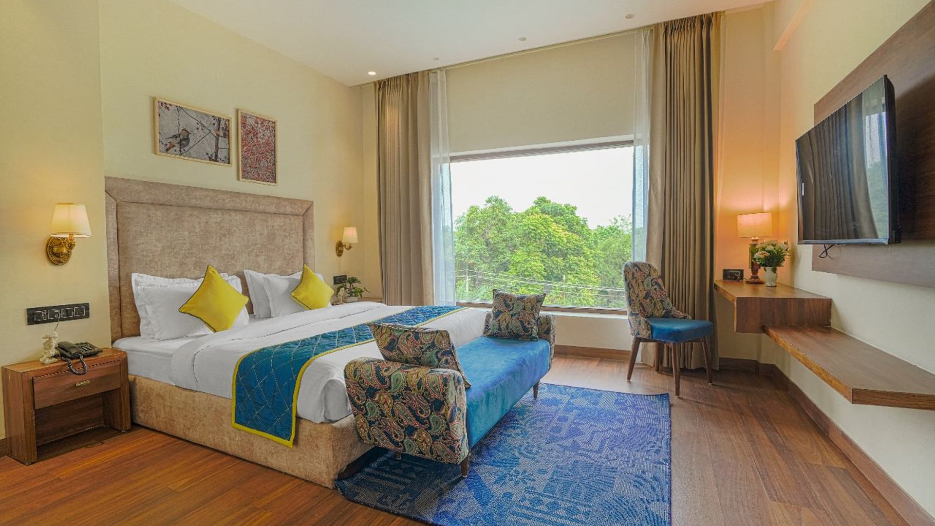 A Super Deluxe room at Escala Hotel, with a blue bed runner, a patterned armchair, a television opposite