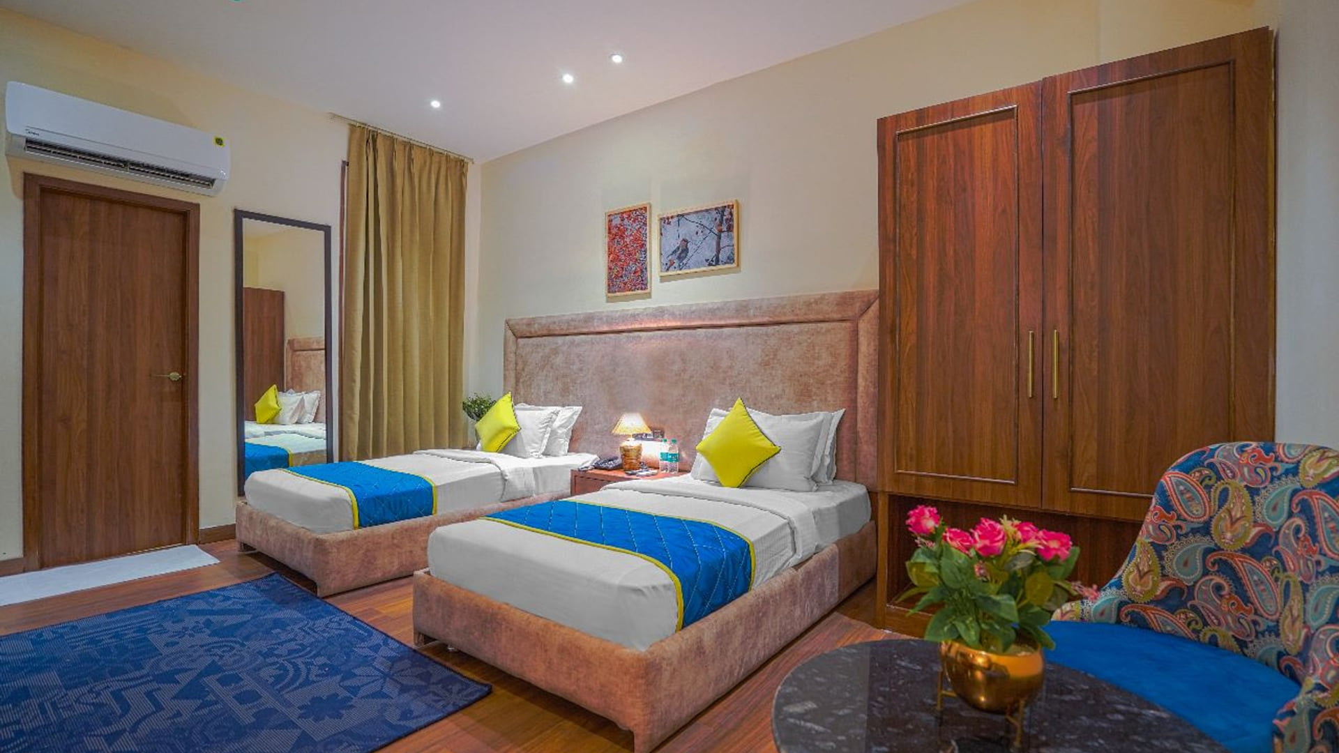 A twin-bedded guest room at Escala Hotel, with two single beds under blue runners, a tall wardrobe