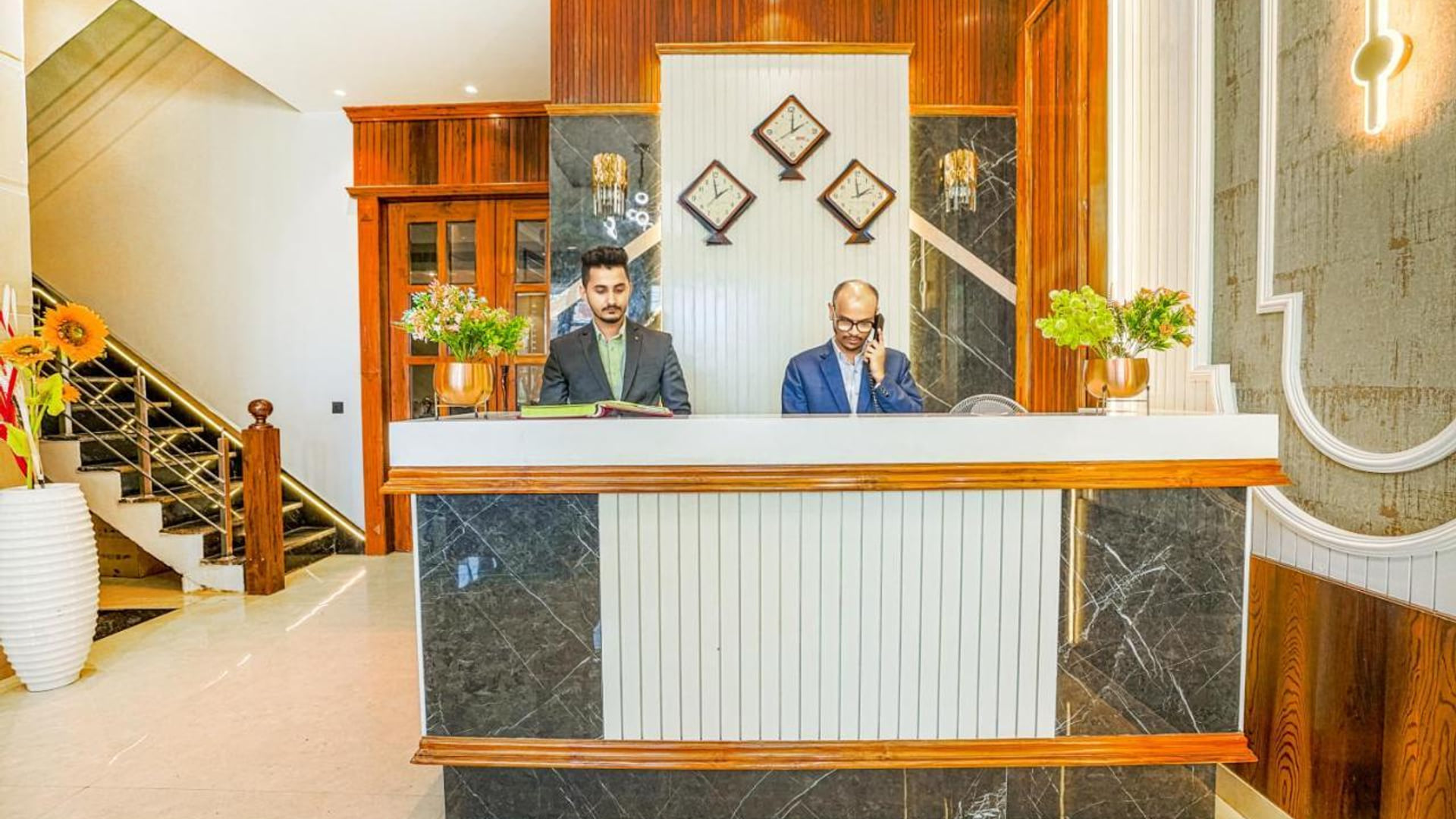 The reception desk at Grand Cabbana, faced in dark marble with two members of staff behind it