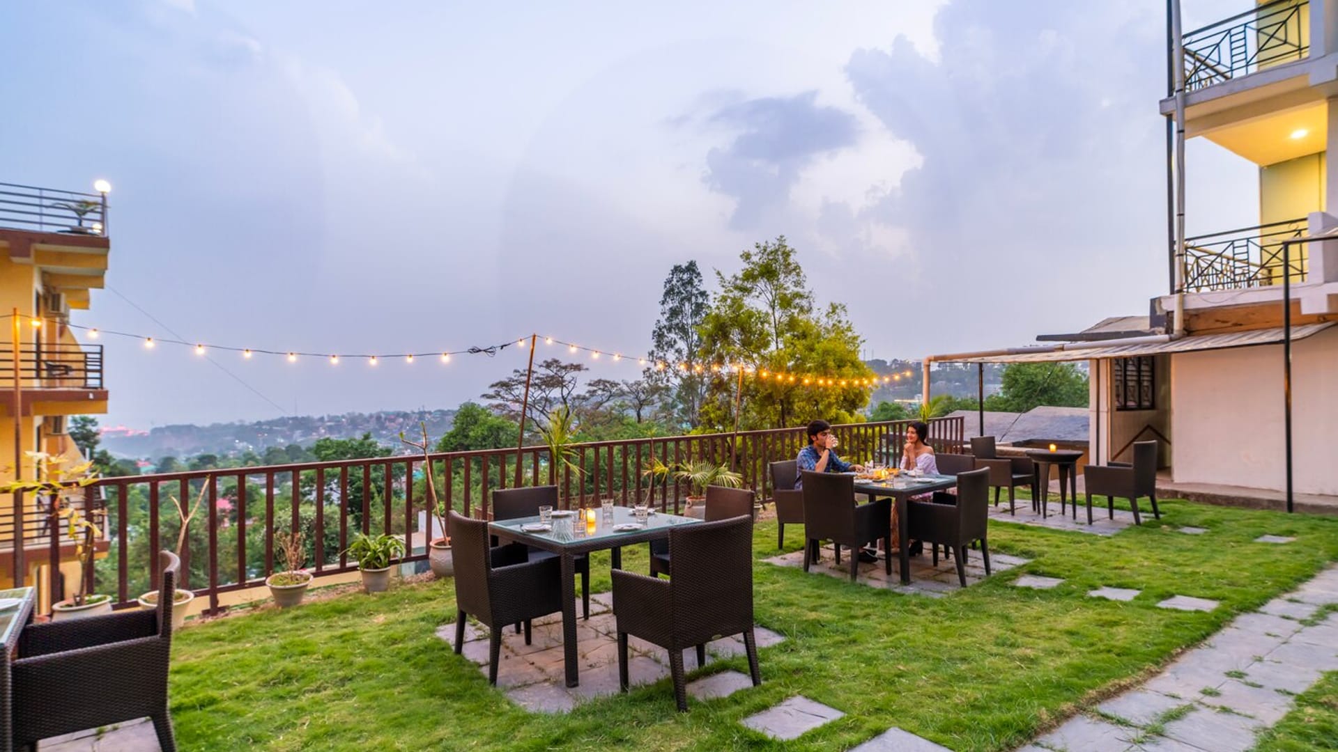 Outdoor dining on the lawn at Hotel Karnika, with tables and chairs set under strings of lights