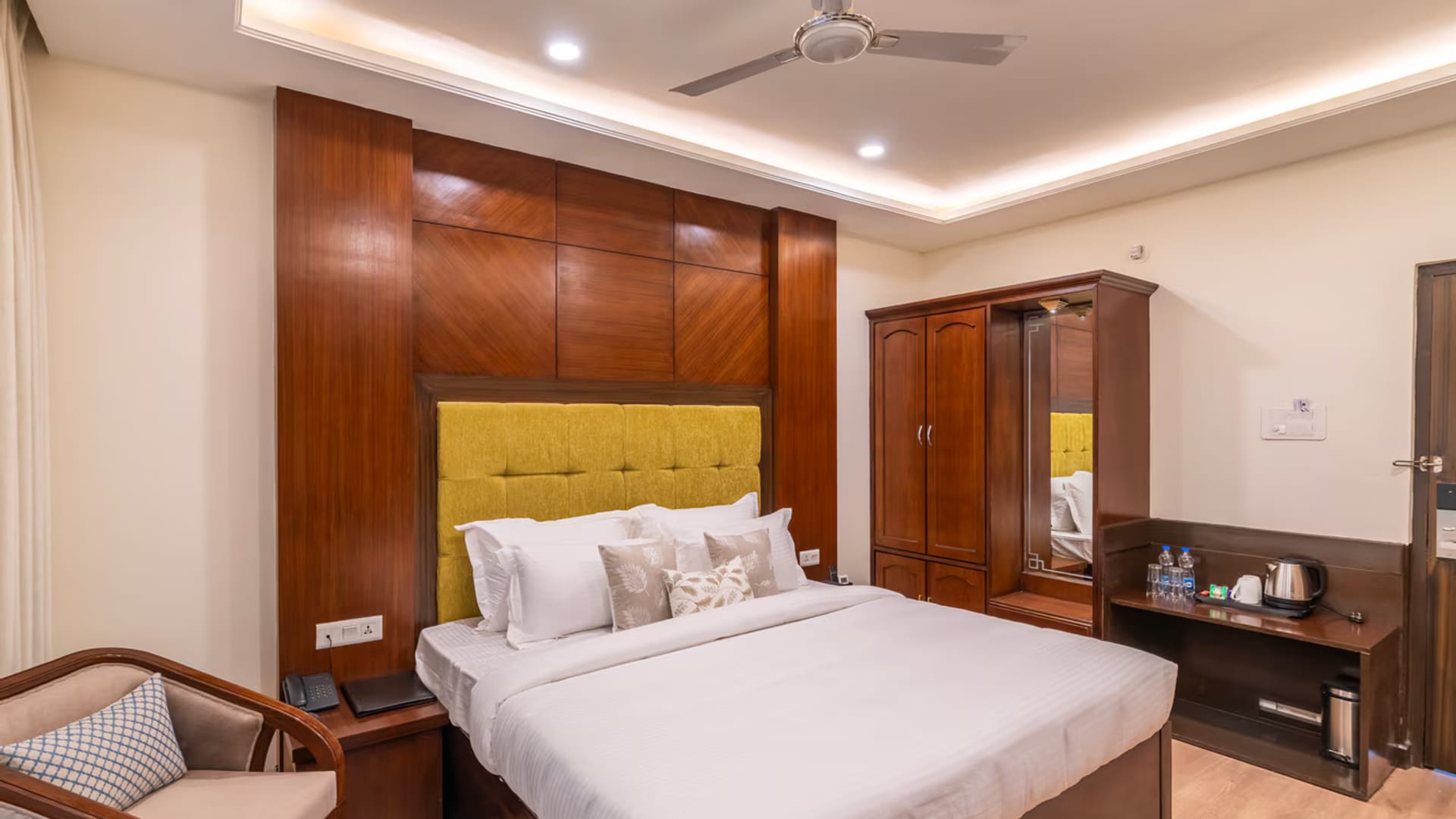 A Standard room with mountain view at Hotel Karnika, with a yellow padded headboard, a wardrobe