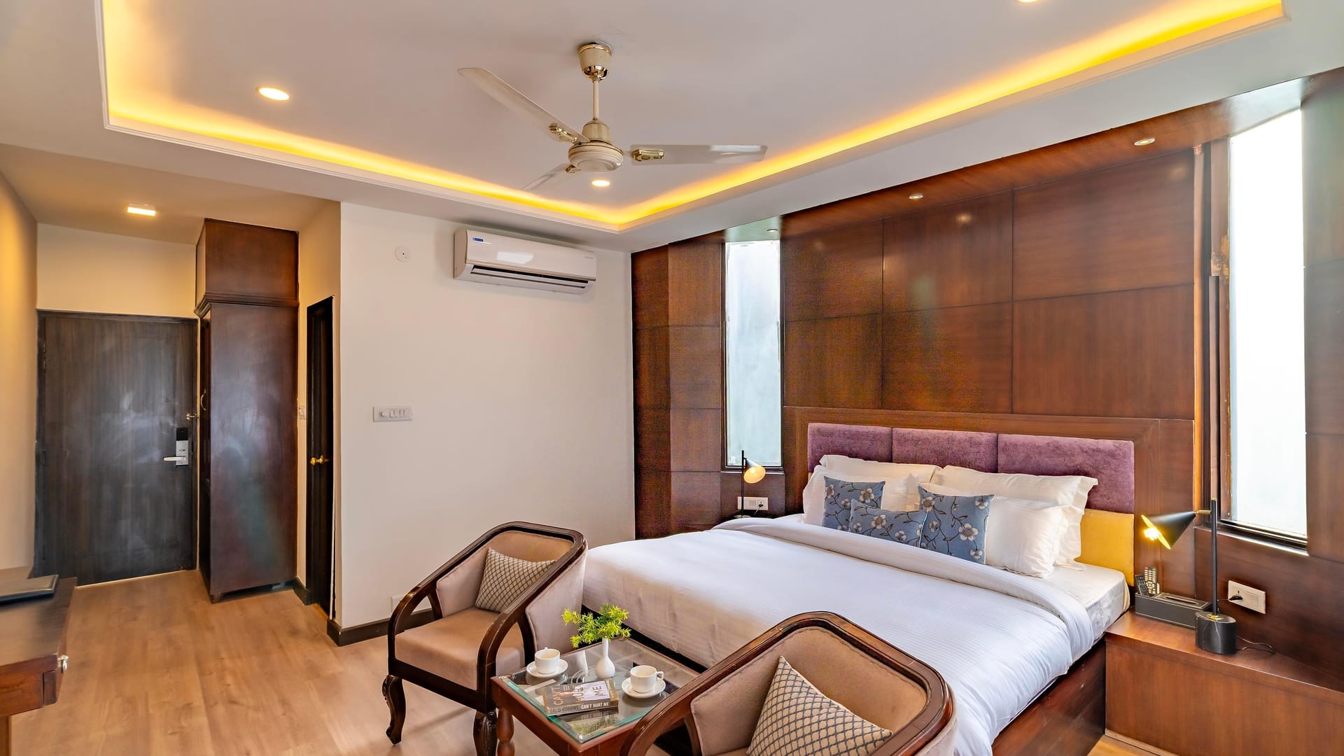 A Super Deluxe room at Hotel Karnika, with a padded headboard set into timber panelling