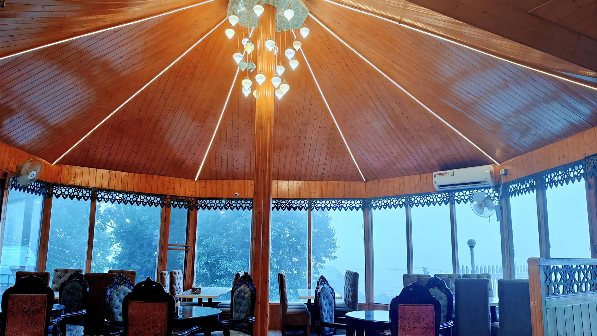 The restaurant at Levelup The Heritage Kud, a circular glass-walled room with a timber ceiling radiating from the chandelier