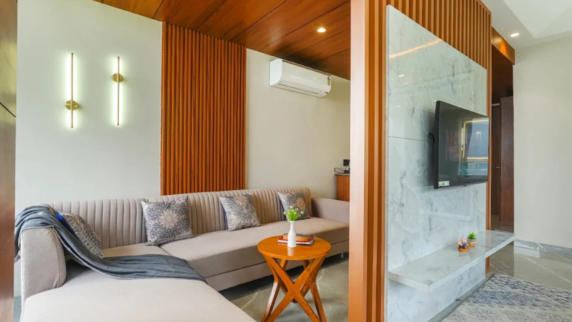 The living area of a suite at White Panda Hotel Divine Peaks, with an L-shaped sofa, a wall-mounted television