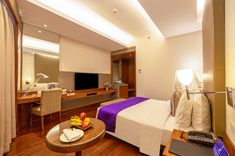 Deluxe Room king bed and work desk at The Anya Hotel, Gurugram