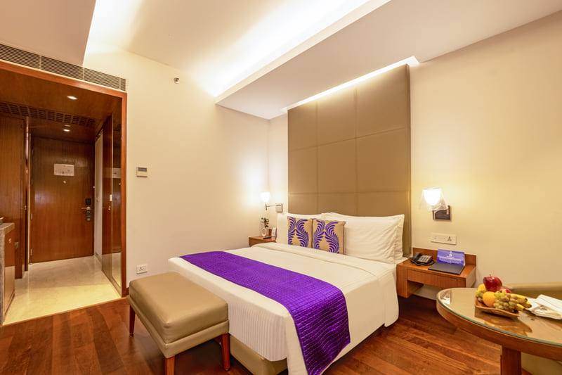 Deluxe Room king bed and seating at The Anya Hotel, Gurugram