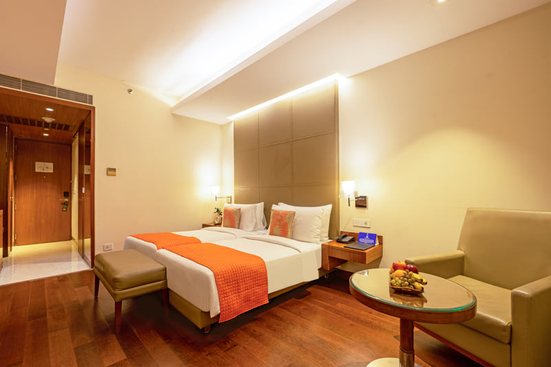 Deluxe Room king bed with armchair at The Anya Hotel, Gurugram