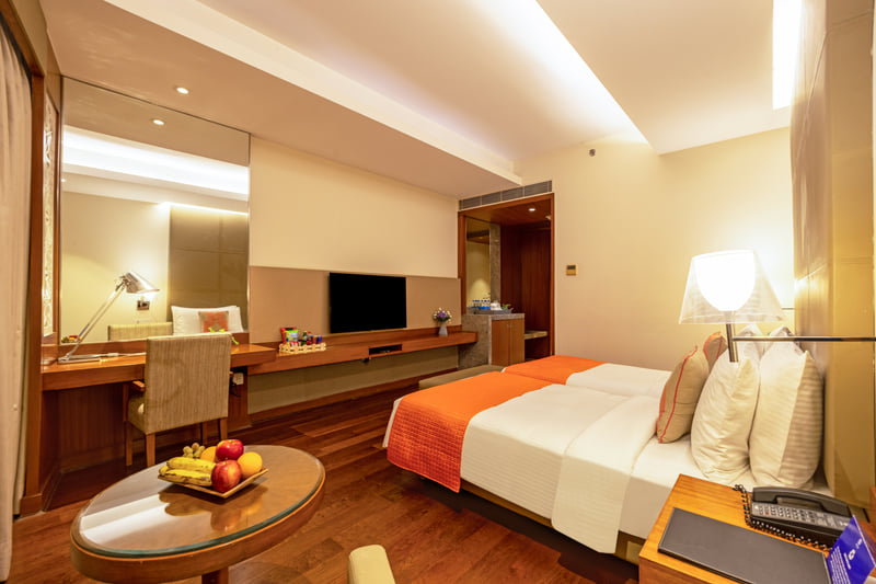 Deluxe Room king bed and dressing table at The Anya Hotel, Gurugram