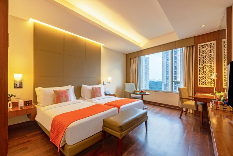 Superior Room twin beds with bench at The Anya Hotel, Gurugram