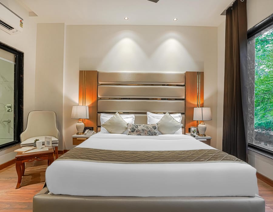 A Superior room at Aura Bliss, with a padded headboard, bedside lamps, an armchair by the window