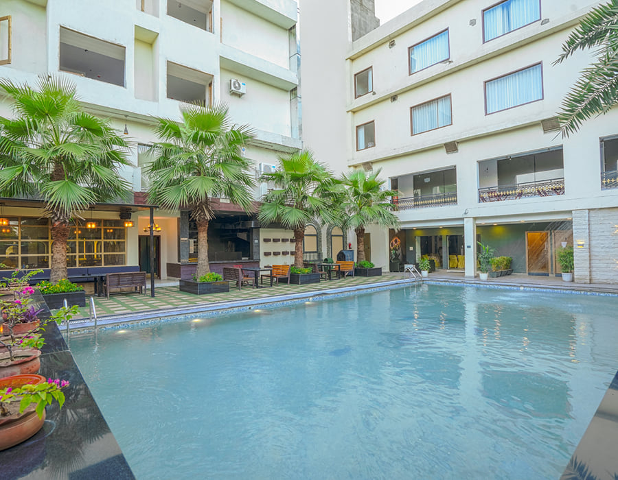 The swimming pool at Escala Hotel, set in a planted courtyard with palms along the edge and the hotel rising on the far side