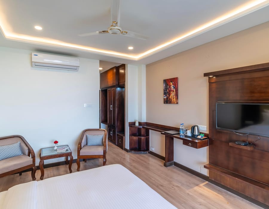 A Deluxe room with valley view at Hotel Karnika, with two armchairs around a small table, a wardrobe