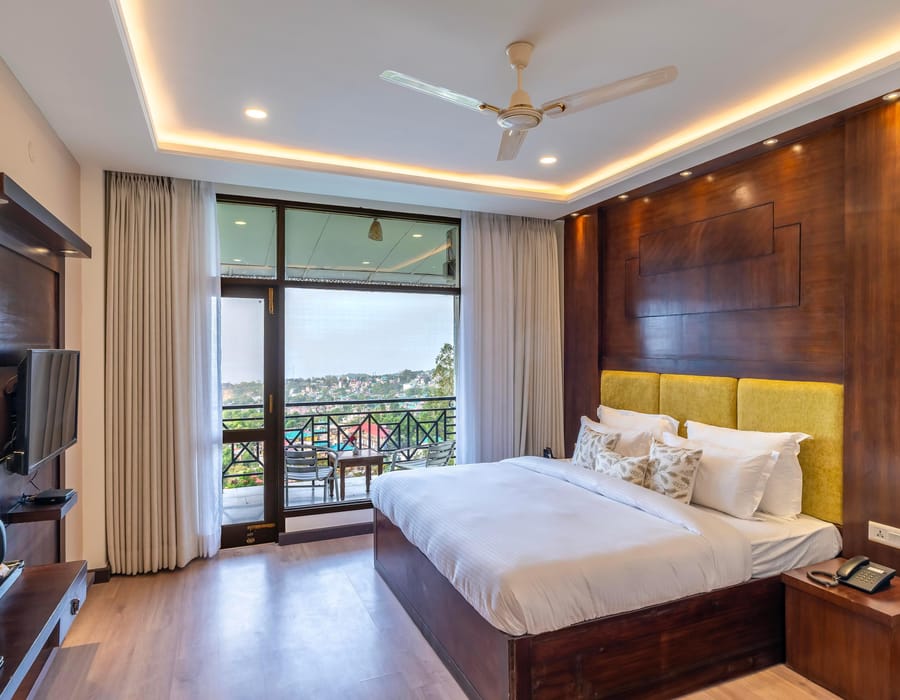 The Maharaja Suite at Hotel Karnika, with a yellow padded headboard, a television opposite