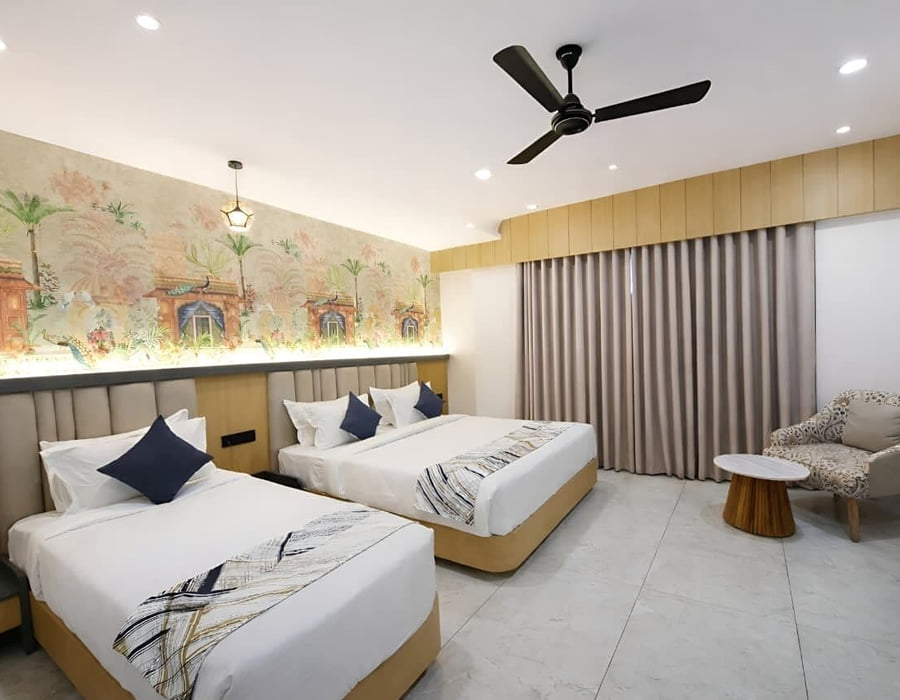 The Family Interconnected room at Hotel Shree Radhe By White Panda, with two beds below a painted mural of arches