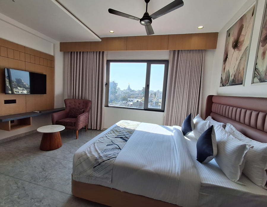 A Temple and Sea View room at Hotel Shree Radhe By White Panda, with a padded headboard, a television opposite and a window