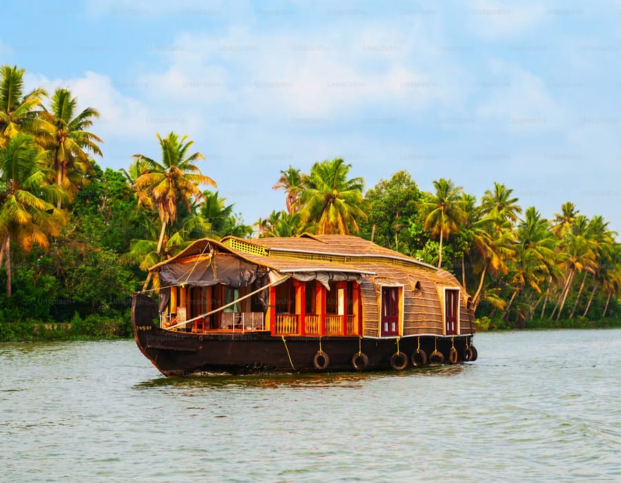 Long wooden country boat gliding across calm Kumbalanghi backwaters with palm-lined banks, Kochi
