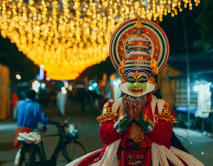 Kathakali dancer in green face paint, red lips, white chutti frame and towering ornate headdress, Kochi