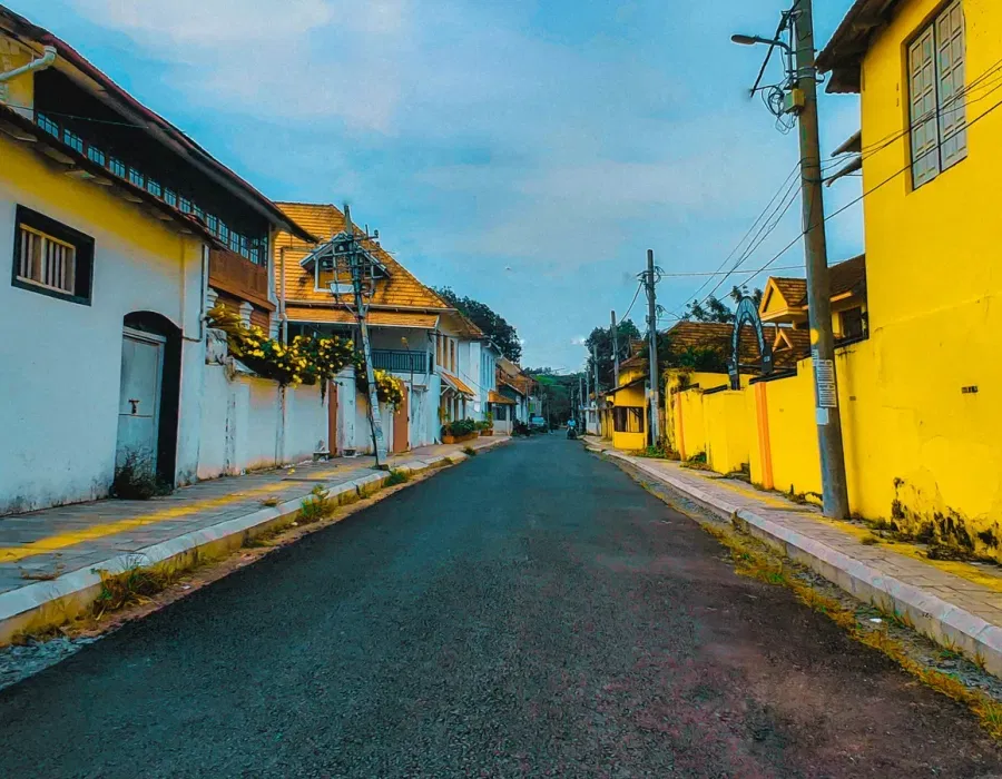Narrow Jew Town lane in Mattancherry lined with heritage shopfronts in blue, yellow and green, Kochi