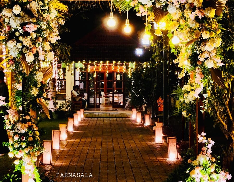 Courtyard pavilion set for an event with white drapes, floral pillars and traditional lamps, Sanskreti, Kumbalanghi, Kochi