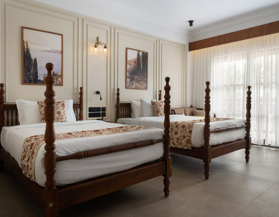 Garden View Room with two four-poster twin beds set under a wide landscape painting