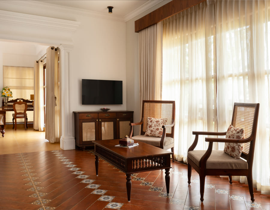 Heritage Suite living room with a green upholstered sofa, wooden coffee table and a Kerala mural on the wall