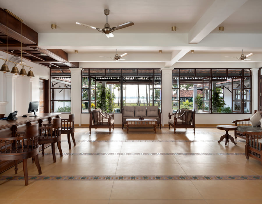 Sanskreti reception lounge with cushioned wooden sofas, a chandelier and large windows overlooking the lake