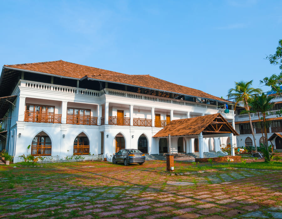 Sanskreti facade with arched verandahs, sloping tiled roof and a courtyard garden in front