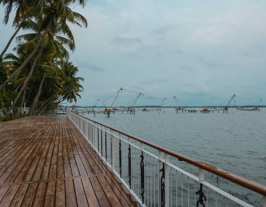 Wooden infinity deck at Sanskreti with cantilevered Chinese fishing nets reaching over the Vembanad backwaters