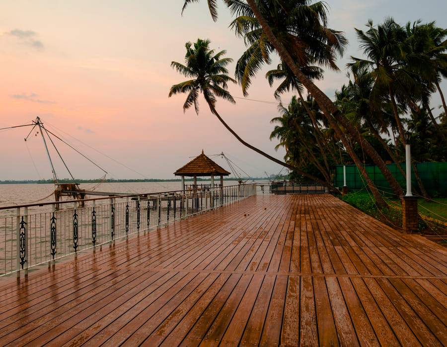 Sanskreti waterfront deck with a wooden gazebo and lounge chairs over the backwater at sunset, Kumbalanghi, Kochi