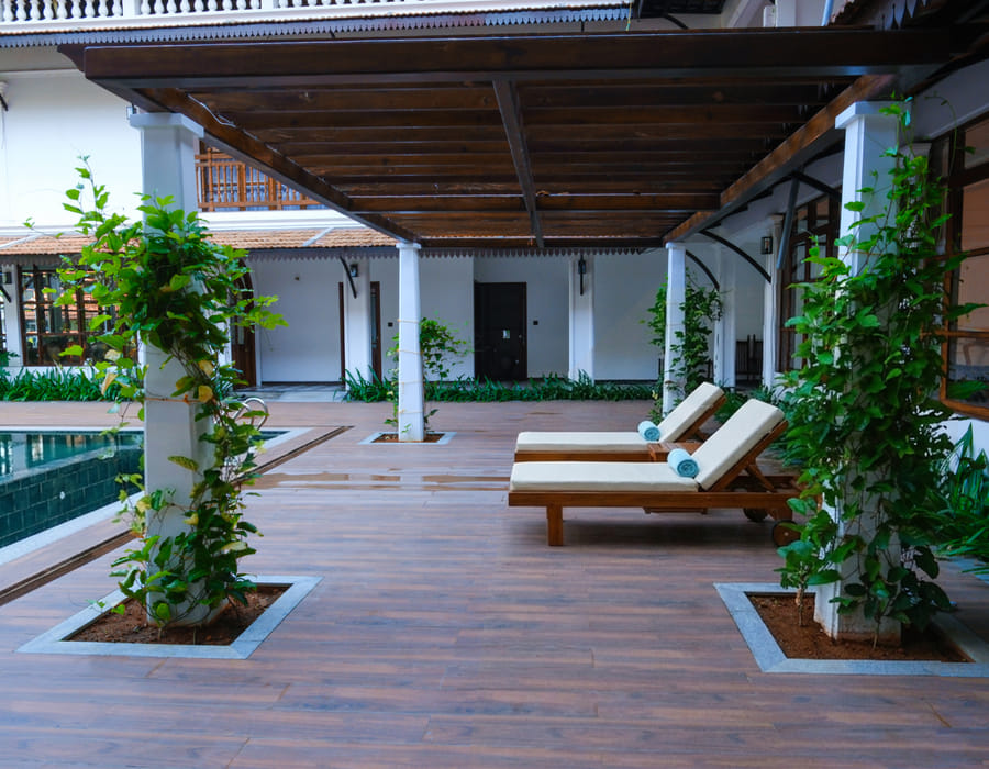 Poolside courtyard at Sanskreti with a red-tiled pergola, potted plants and traditional lamps beside the pool