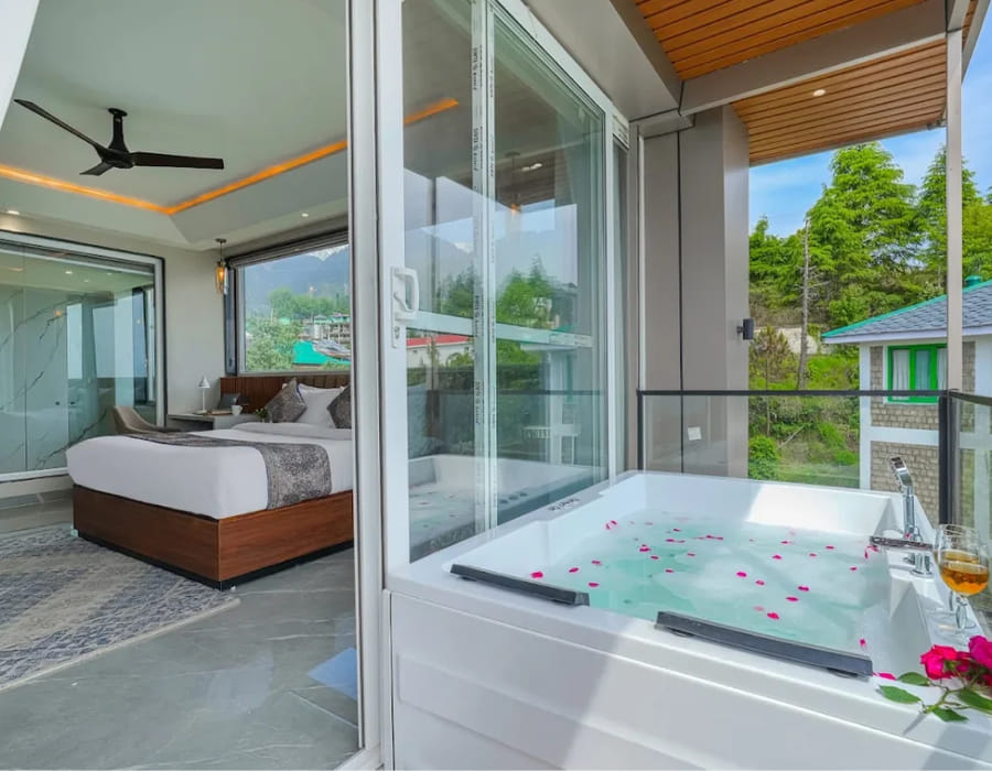 The Jacuzzi Suite Room at White Panda Hotel Divine Peaks, with a jacuzzi tub scattered with rose petals beside a glass wall