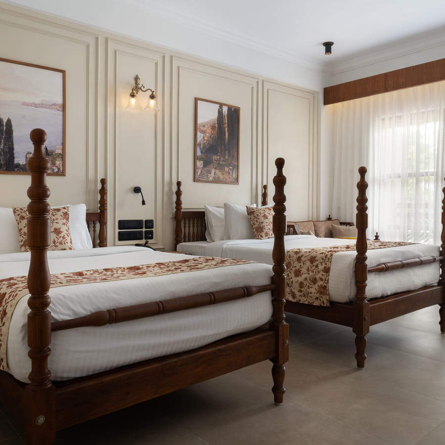 Garden View Room with two four-poster twin beds set under a wide landscape painting, Sanskreti